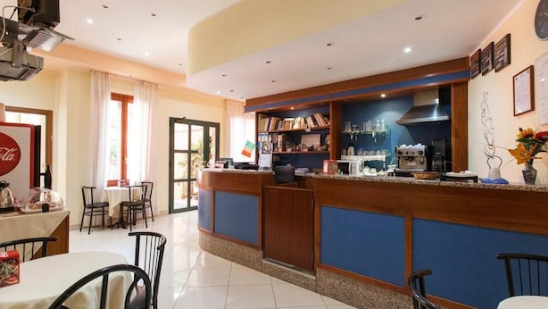 A hotel lobby with a reception desk, seating area, and a view of the outside. - Hotel Greco (Milan)
