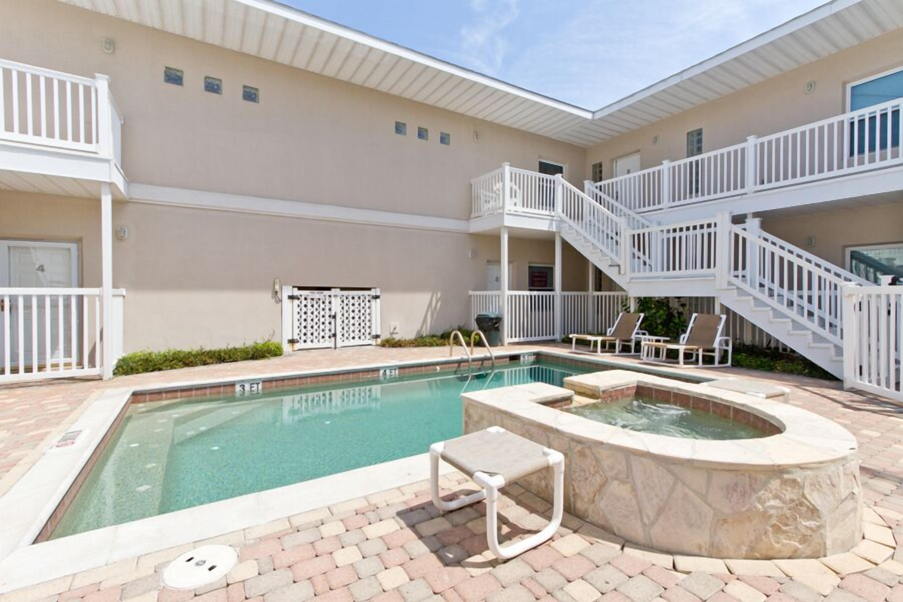 A pool area with a hot tub, lounge chairs, and a staircase leading to an upper level.