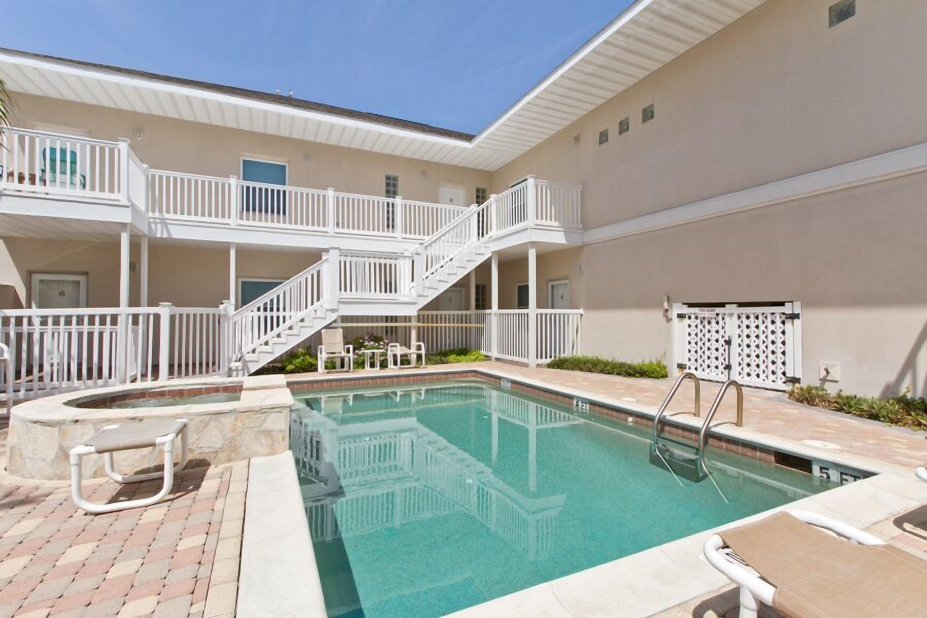 A pool area with a hot tub, a staircase, and outdoor seating.