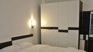 A modern hotel room with a large bed, a wardrobe, and a wall-mounted air conditioning unit. - Sri Samui Hotel (Koh Samui)
