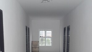 A spacious, empty hallway with a glossy floor, white walls, and a large window at the end. - Sri Samui Hotel (Koh Samui)
