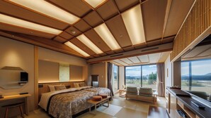 A modern hotel room with a large bed, a desk, a chair, and a balcony with a view of the mountains. - KINUGAWA GRAND HOTEL YUME no TOKI (Nikko)