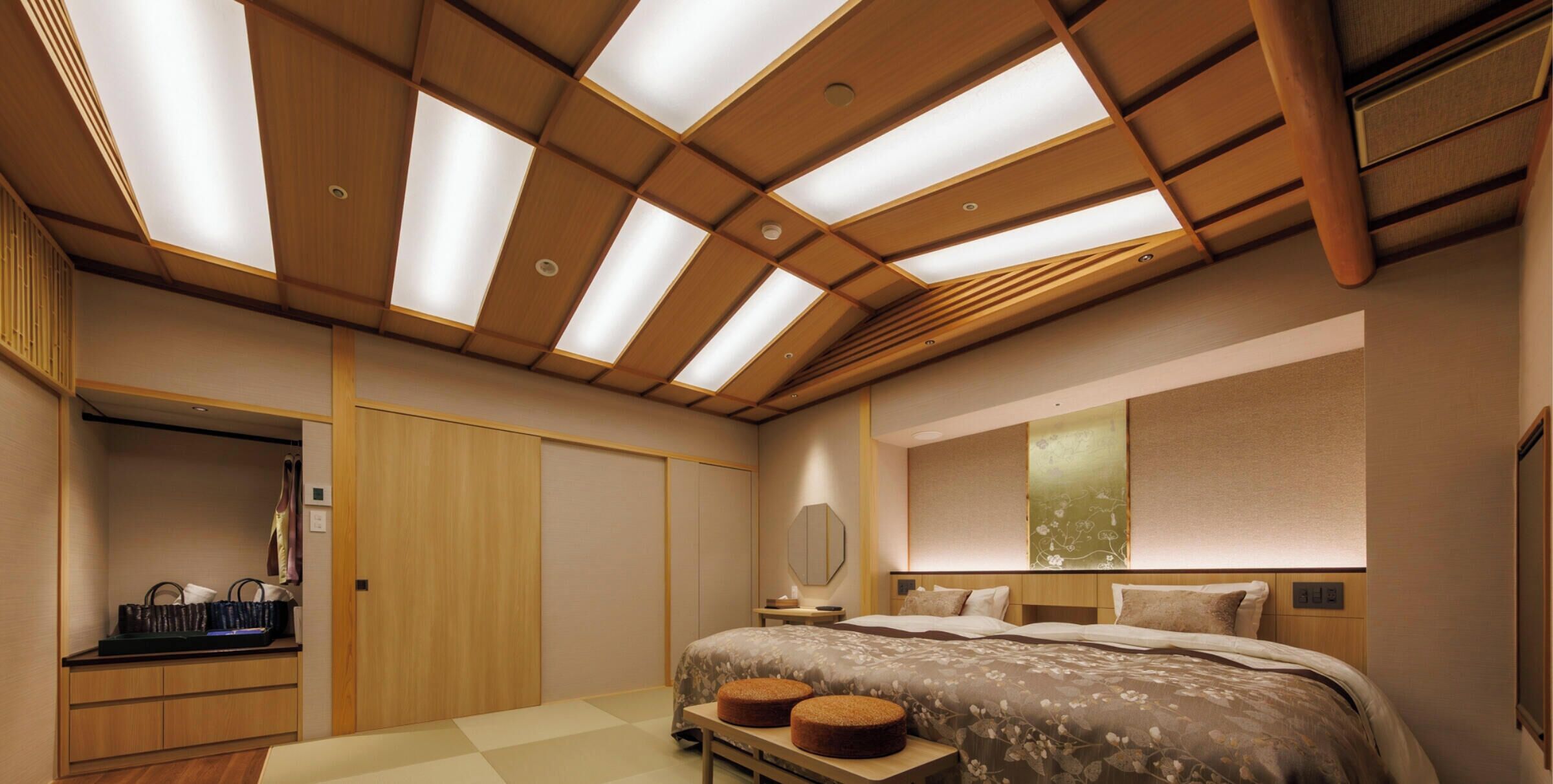 A bedroom with a skylight ceiling, a bed with a floral bedspread, a bedside table, and a wardrobe.