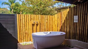 A hot tub in a backyard with a wooden fence and a black garage door. - Ciribaí Praia Hotel (São Sebastião)