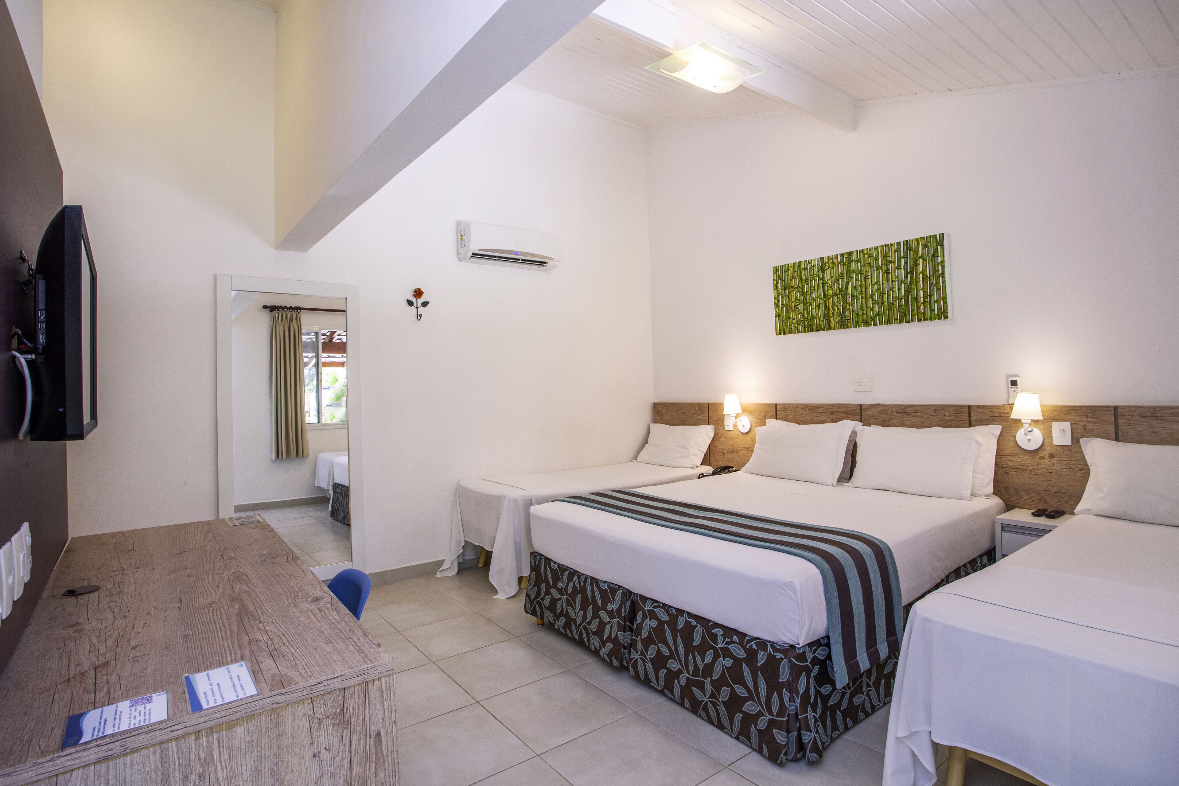A hotel room with two beds, a desk, and a television.
