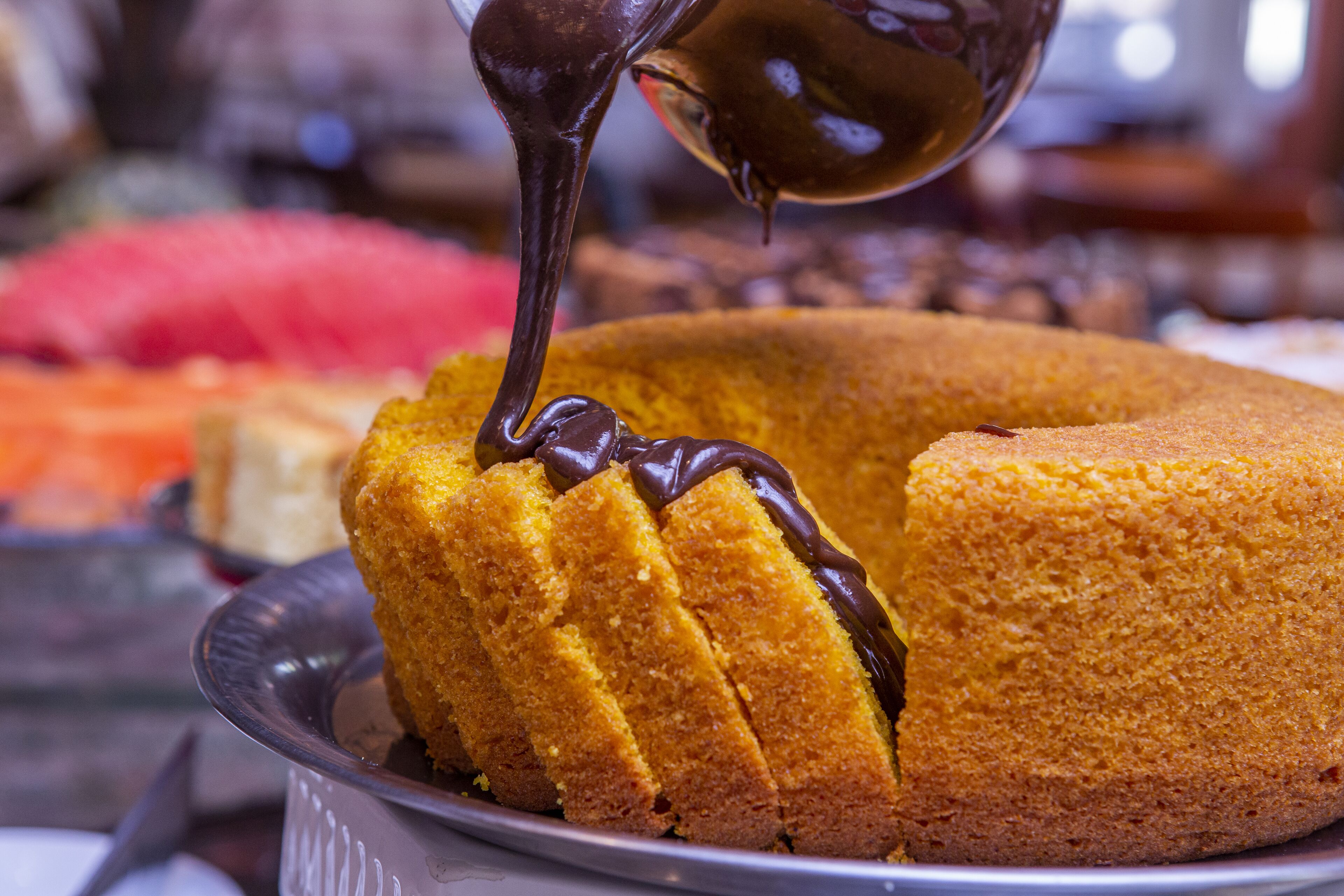A bundt cake with chocolate sauce being poured over it.