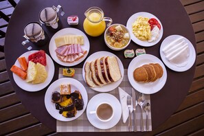Enjoy a delicious breakfast spread on this beautifully set table, featuring a variety of dishes and refreshing beverages.