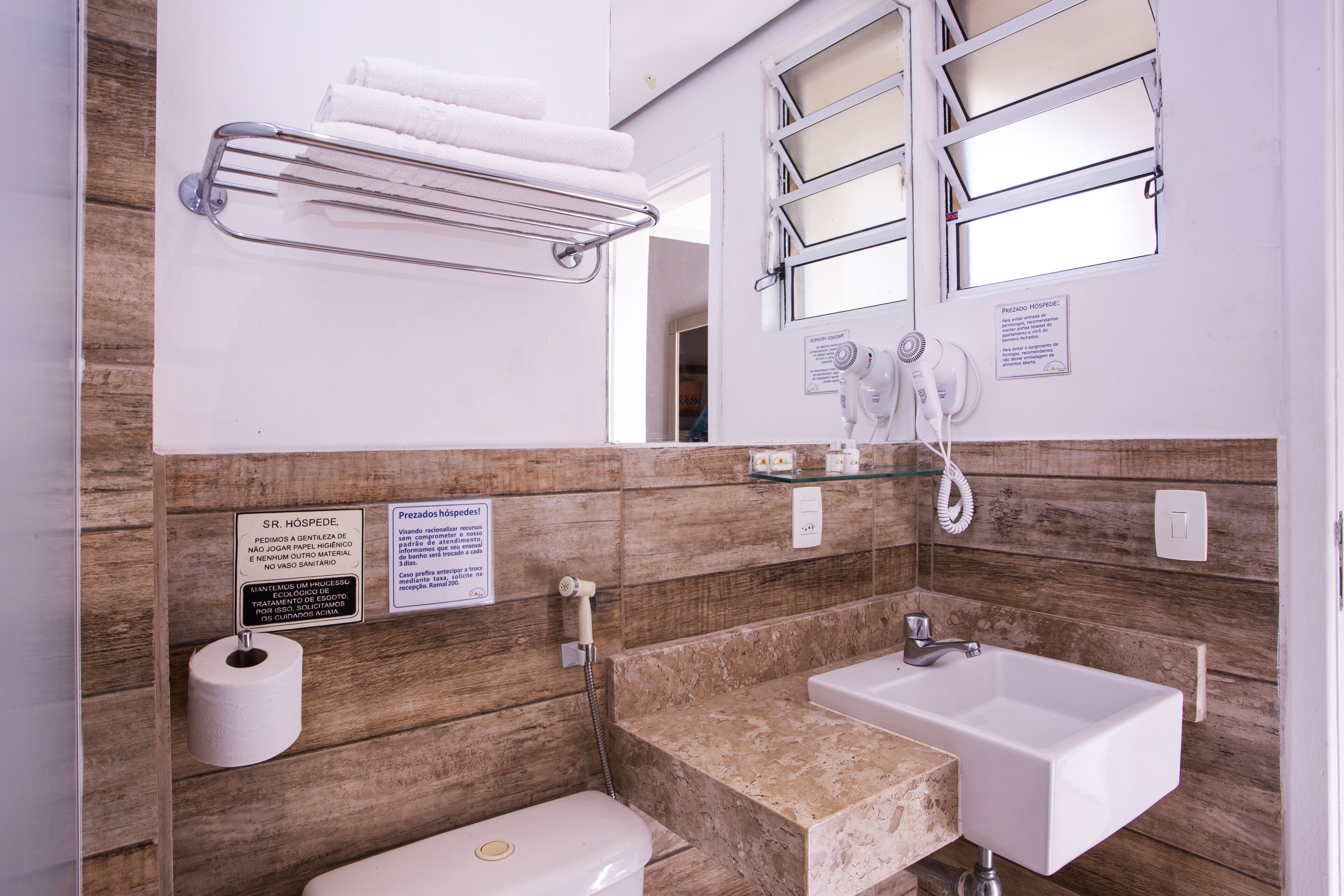 Een badkamer met toilet, wastafel, handdoekrek en douche.