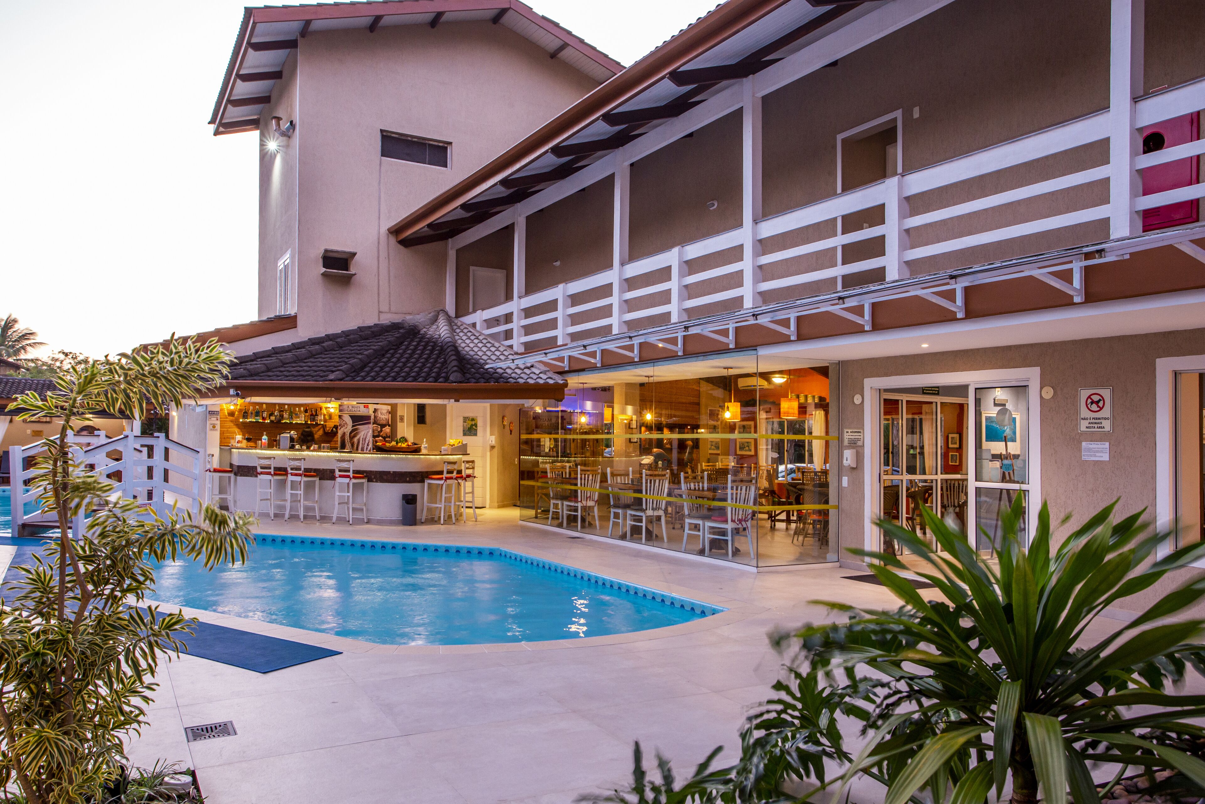 A hotel with a swimming pool, outdoor bar, and multiple dining areas.