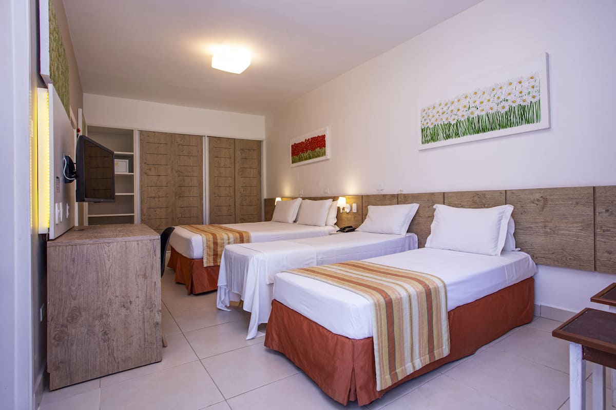 A hotel room with two single beds, a wooden cabinet, a desk, and a wardrobe.