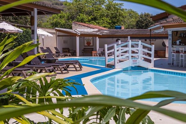 Relax by the serene pool surrounded by lounge chairs and lush greenery.