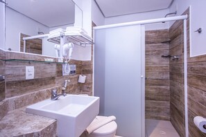 Bathroom features a large sink, toilet, and shower area with a glass door.