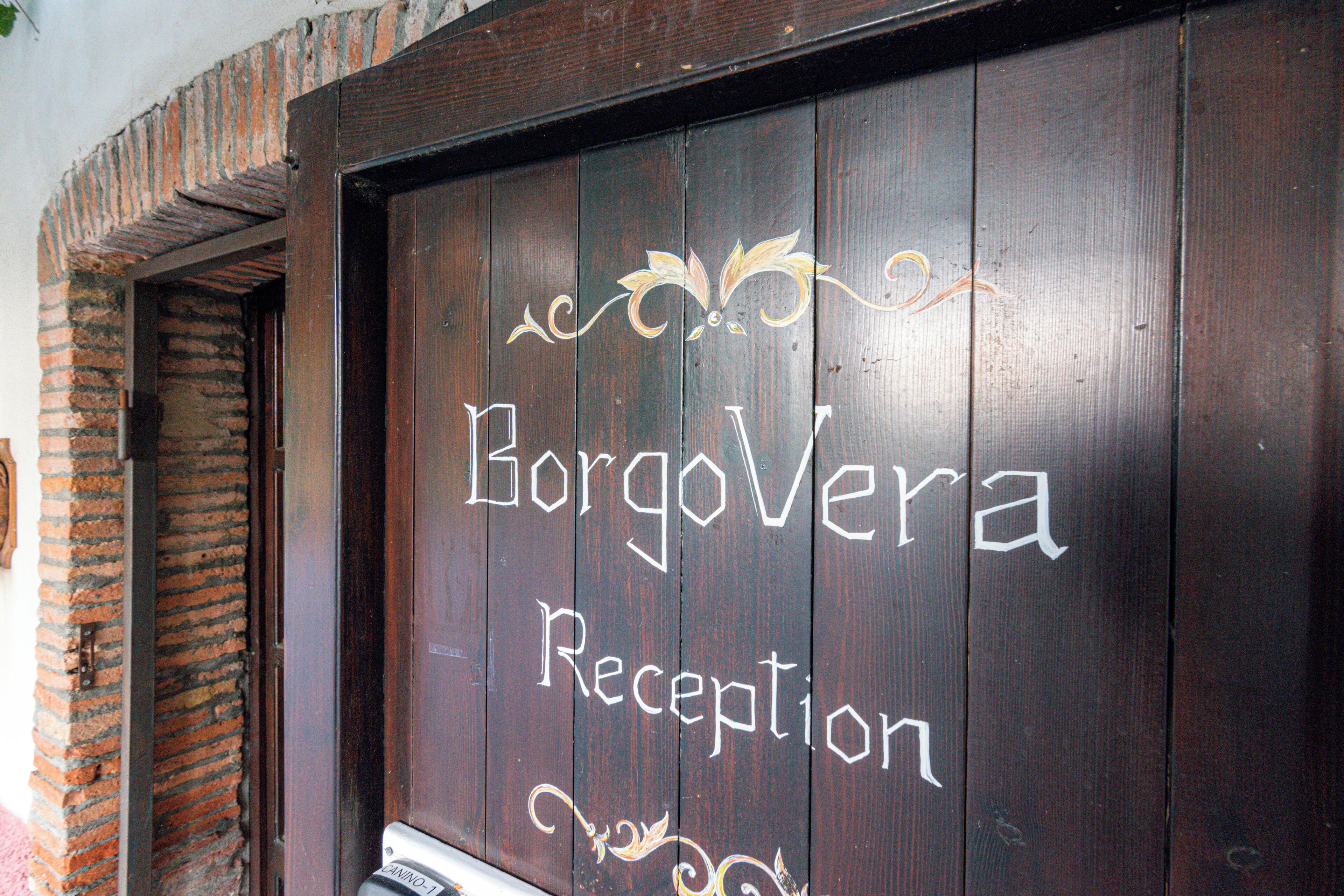 Una porta in legno con la scritta "BorgoVera Reception".