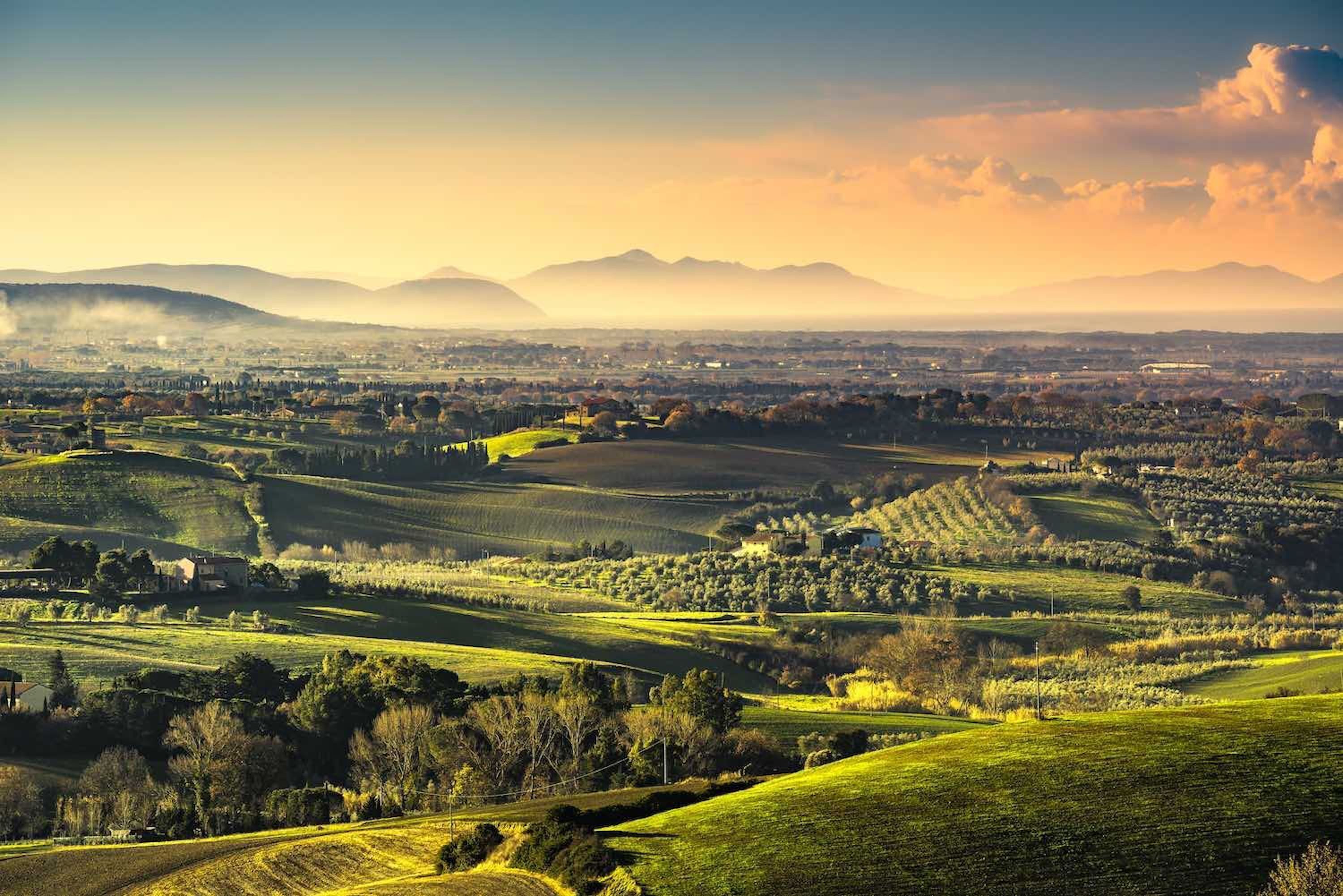A panoramic view of rolling hills, fields, and distant mountains.