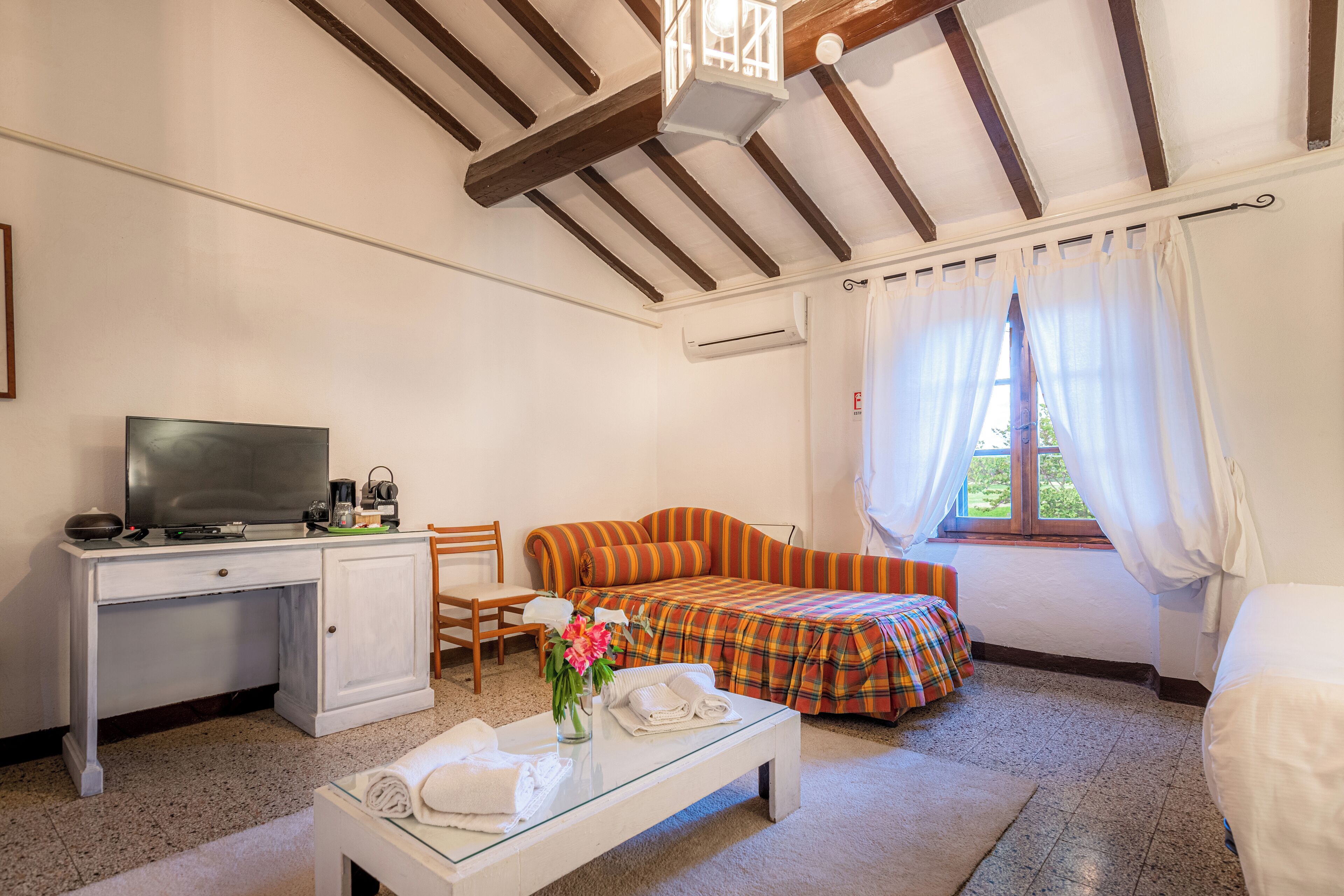 A room with a bed, a sofa, a television, a desk, and a coffee table.