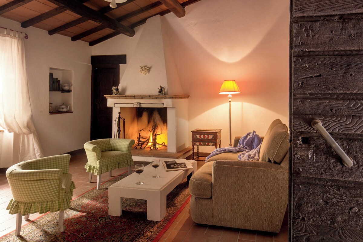 A cozy living room with a fireplace, two green chairs, a beige sofa, and a white coffee table.