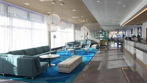 Un vestíbulo moderno con alfombra azul, zona de estar y un mostrador de recepción.