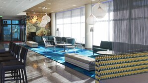 Un lobby moderno con mesa de billar, sillas traslúcidas y una zona de estar con sofás.