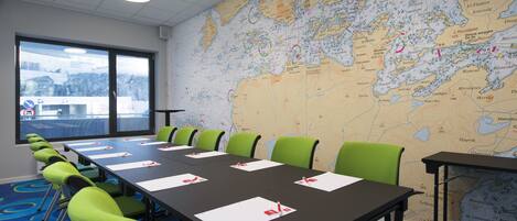 A conference room with a large map on the wall, a long table with chairs, and a view of the outdoors through a window.