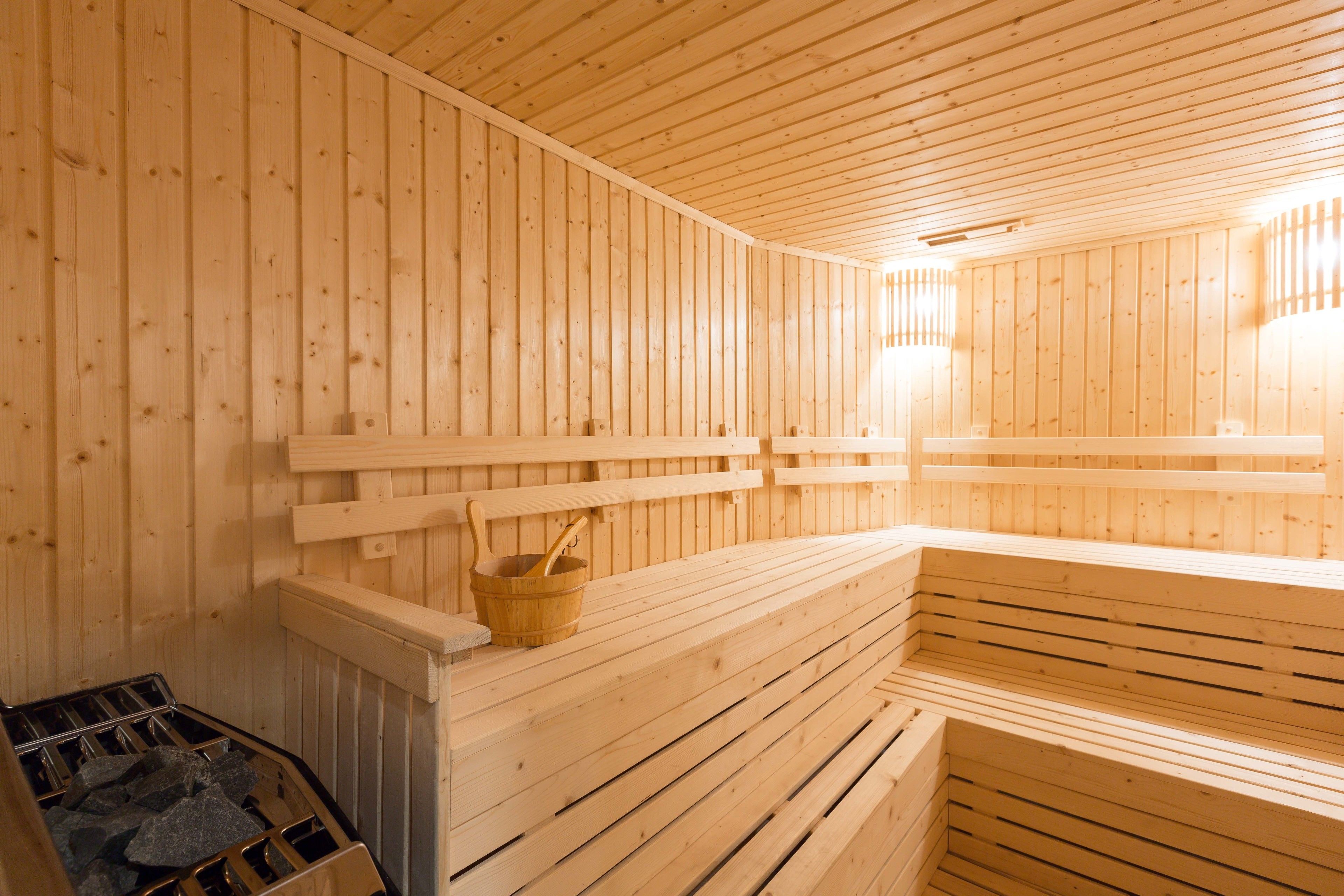 A wooden sauna with benches and a stone heating element.