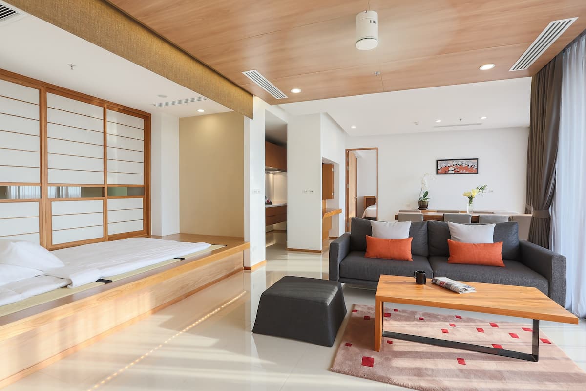 A modern hotel room with a bed, sofa, and coffee table.