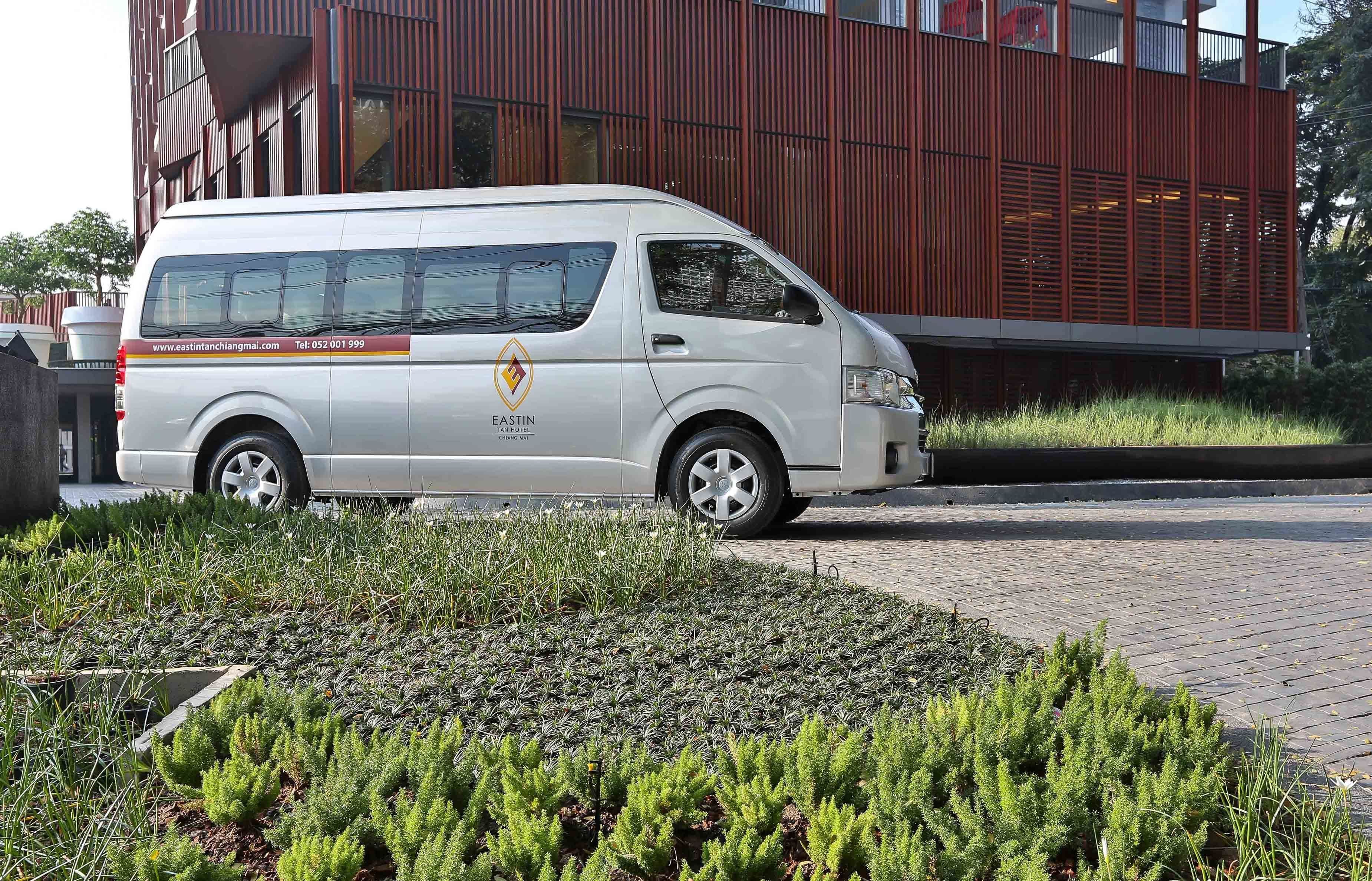 Un furgone bianco parcheggiato di fronte a un edificio moderno, con un indirizzo web e un numero di telefono ben visibili sul fianco.