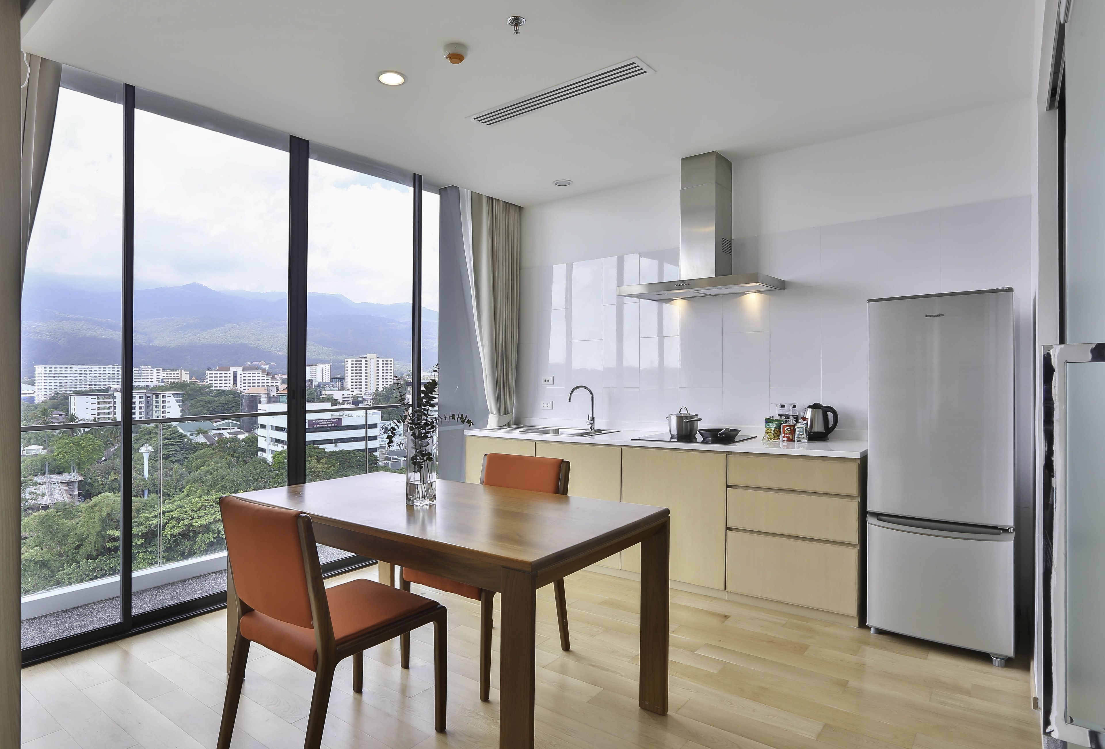 Una cocina moderna con un ventanal amplio, una mesa de comedor y un refrigerador de acero inoxidable.