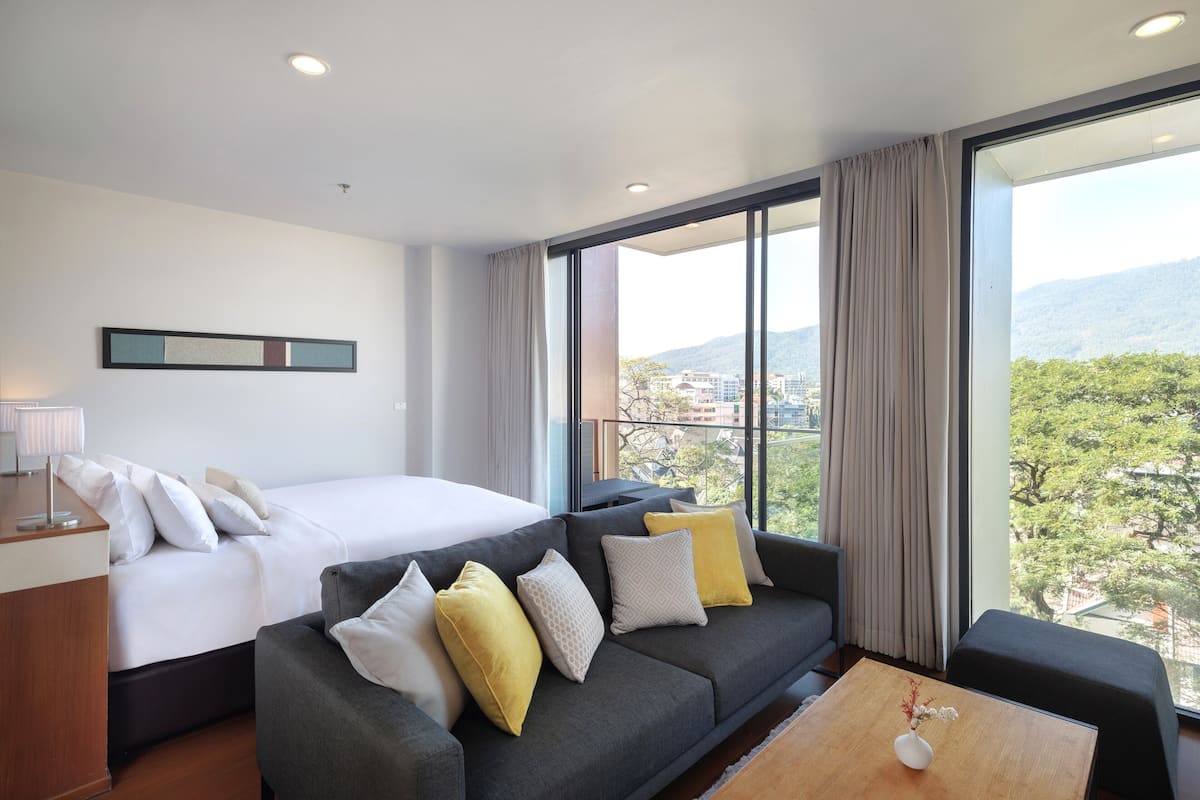 A modern hotel room with a large bed, a sofa, and a coffee table.