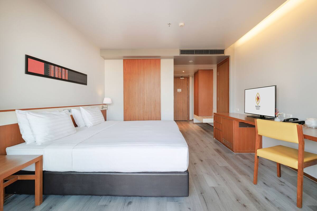 A hotel room with a large bed, wooden desk, and a television.