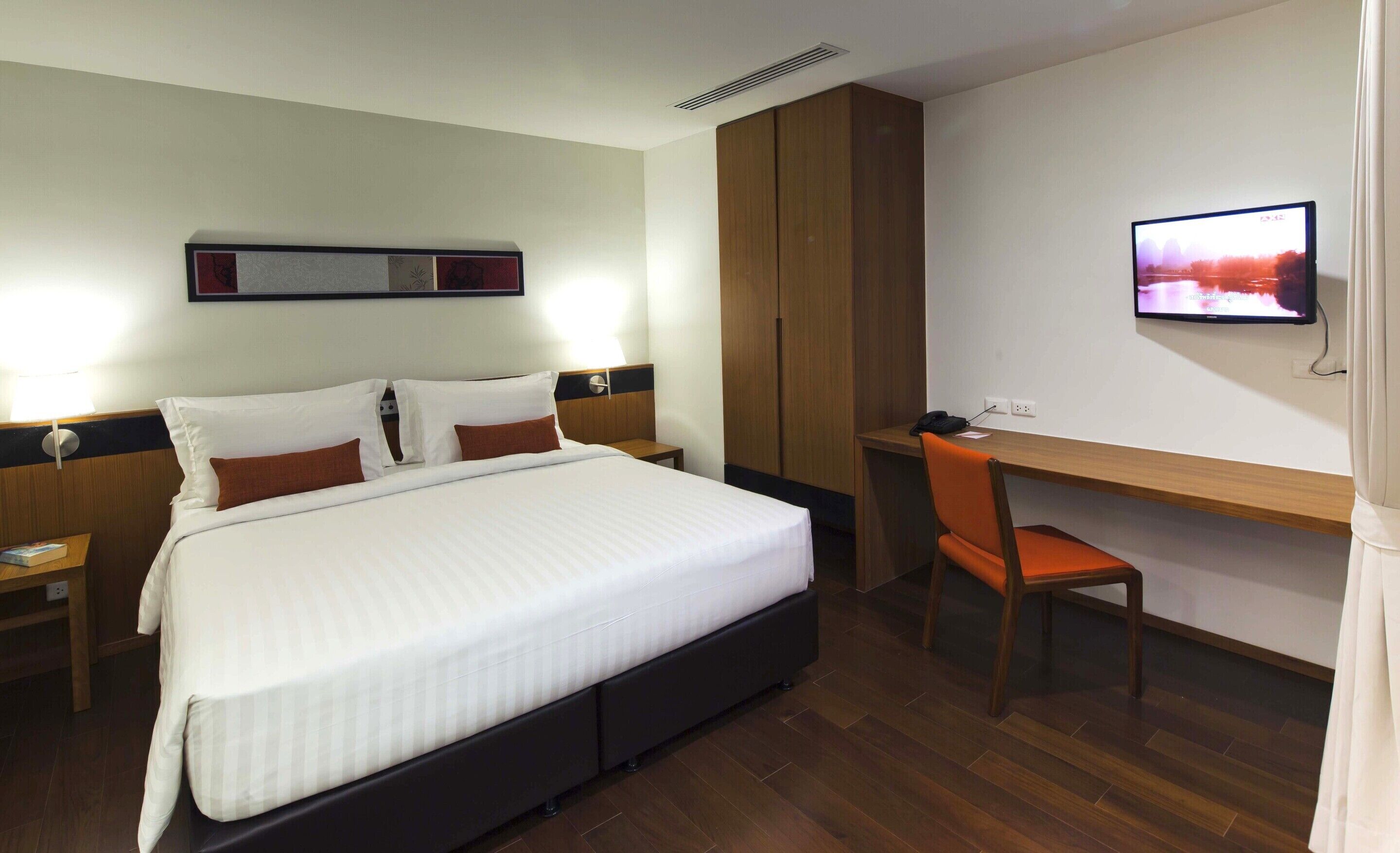 A hotel room with a bed, a desk, and a television.