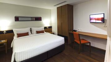 A hotel room with a bed, a desk, and a television.
