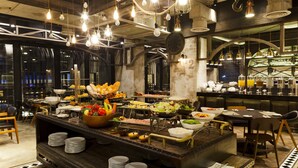 Un bufé con diversos alimentos y una zona de bar con vasos y botellas.