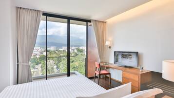 Une chambre d’hôtel avec un lit, un bureau avec un ordinateur, une chaise et un téléviseur.