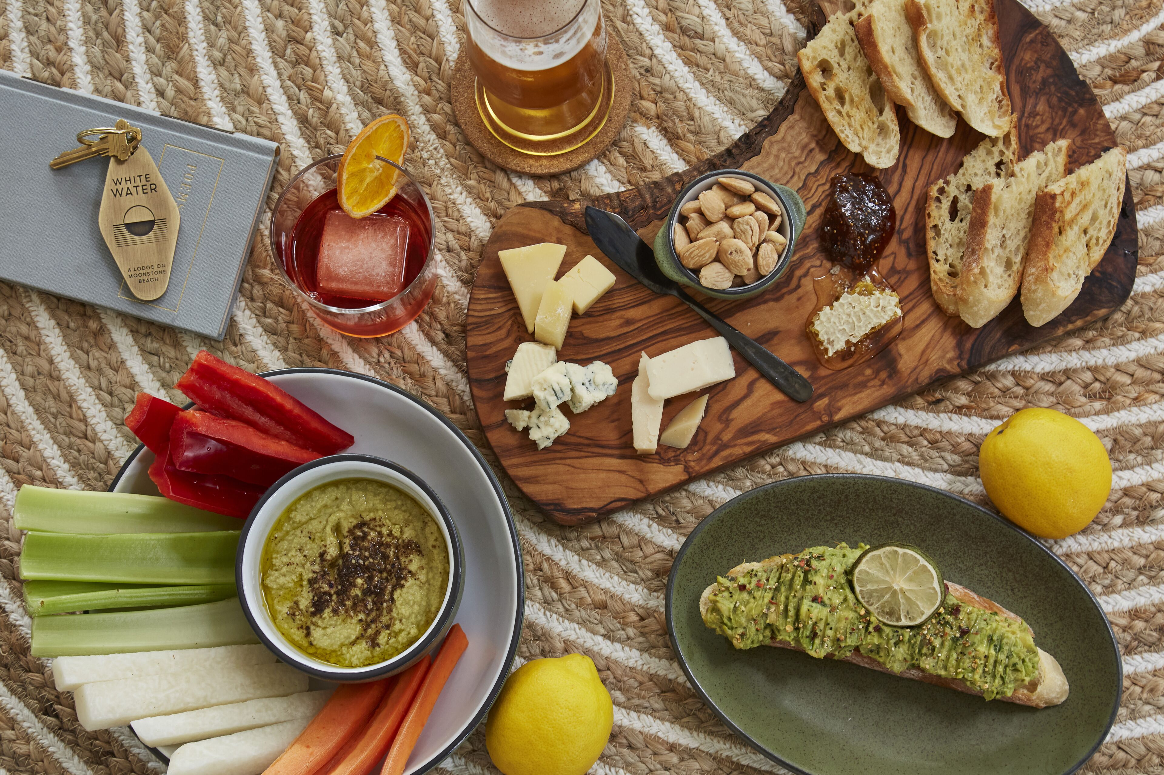 A wooden board with various cheeses, crackers, and a bowl of dip.