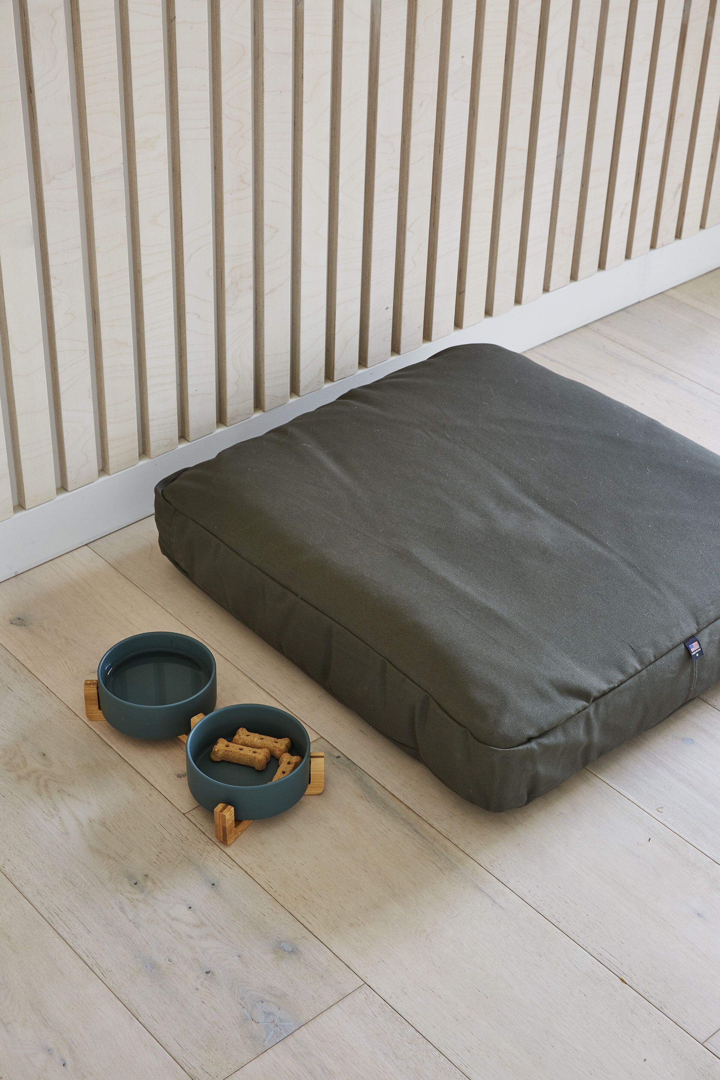 A pet bed with two bowls containing dog treats.