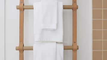 A wooden towel rack with two white towels hanging.