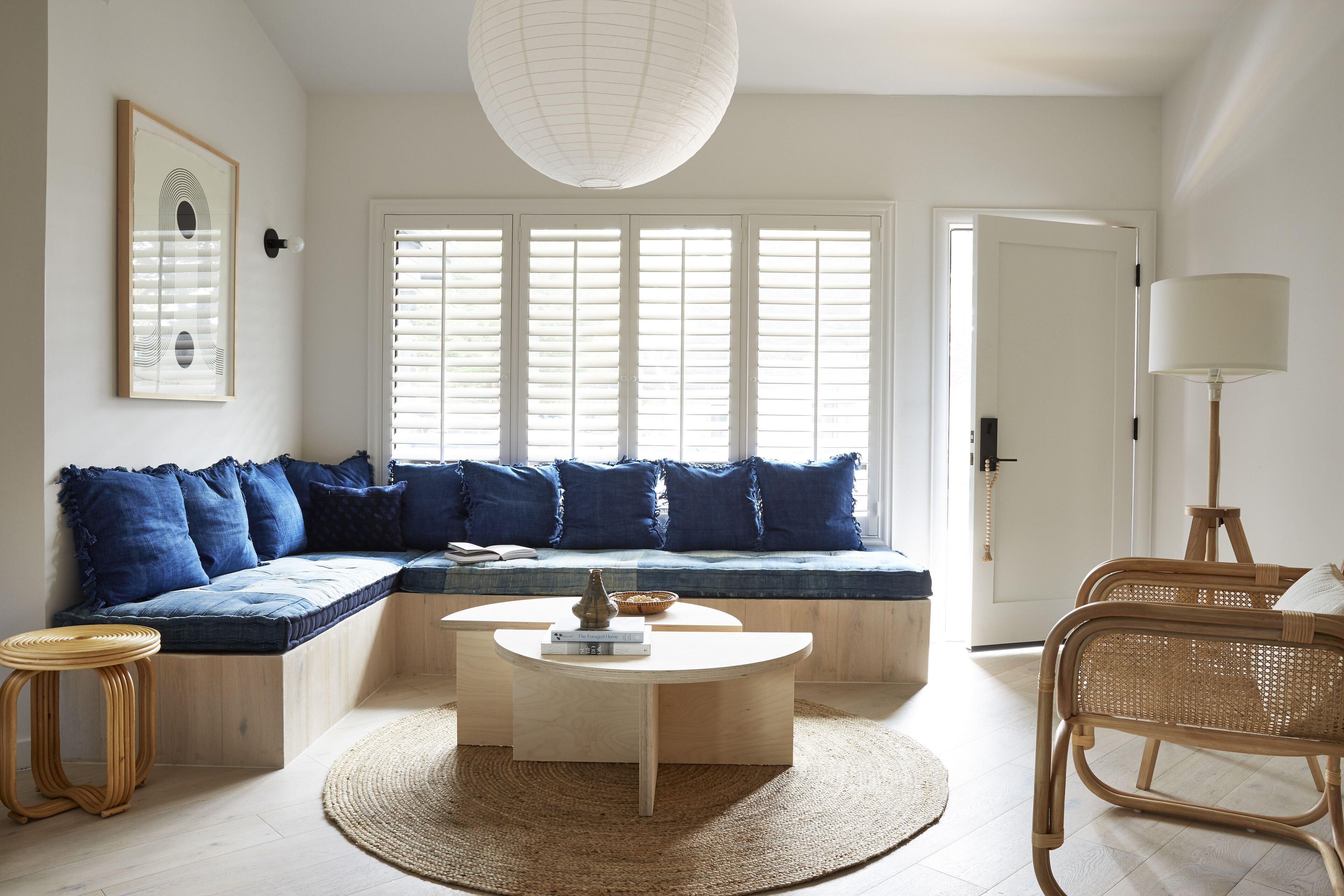 A modern living room with a built-in bench, a round coffee table, and a rattan chair.