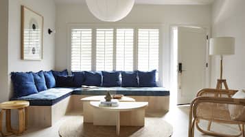 A modern living room with a built-in bench, a round coffee table, and a rattan chair.