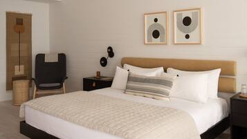 A bedroom with a bed, a chair, a nightstand, and two wall art pieces.