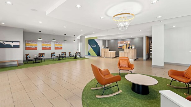 A spacious lobby with a green carpet area, modern furniture, and a reception desk.