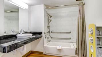 A bathroom with a white sink, black countertop, and a shower with a glass door.