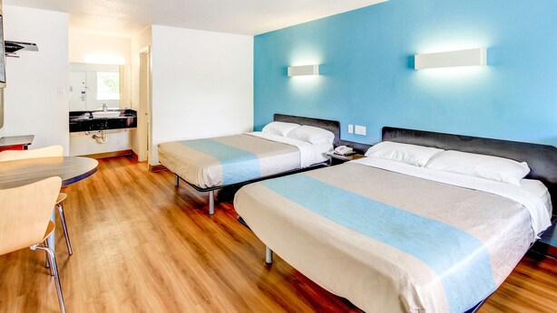 A hotel room with two beds, a small kitchenette, a dining table, and a bathroom visible through an open door. - Motel 6 Waco, TX - Lacy Lakeview (Waco)