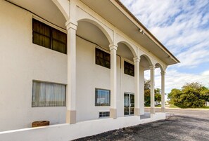 Un edificio con fachada blanca, varias ventanas y un porche cubierto.