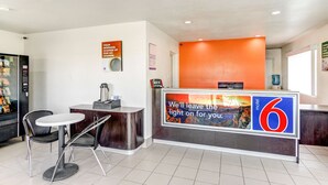 A motel reception area with a counter, two chairs, a vending machine, and a sign indicating the motel number. - Motel 6 Waco, TX - Lacy Lakeview (Waco)