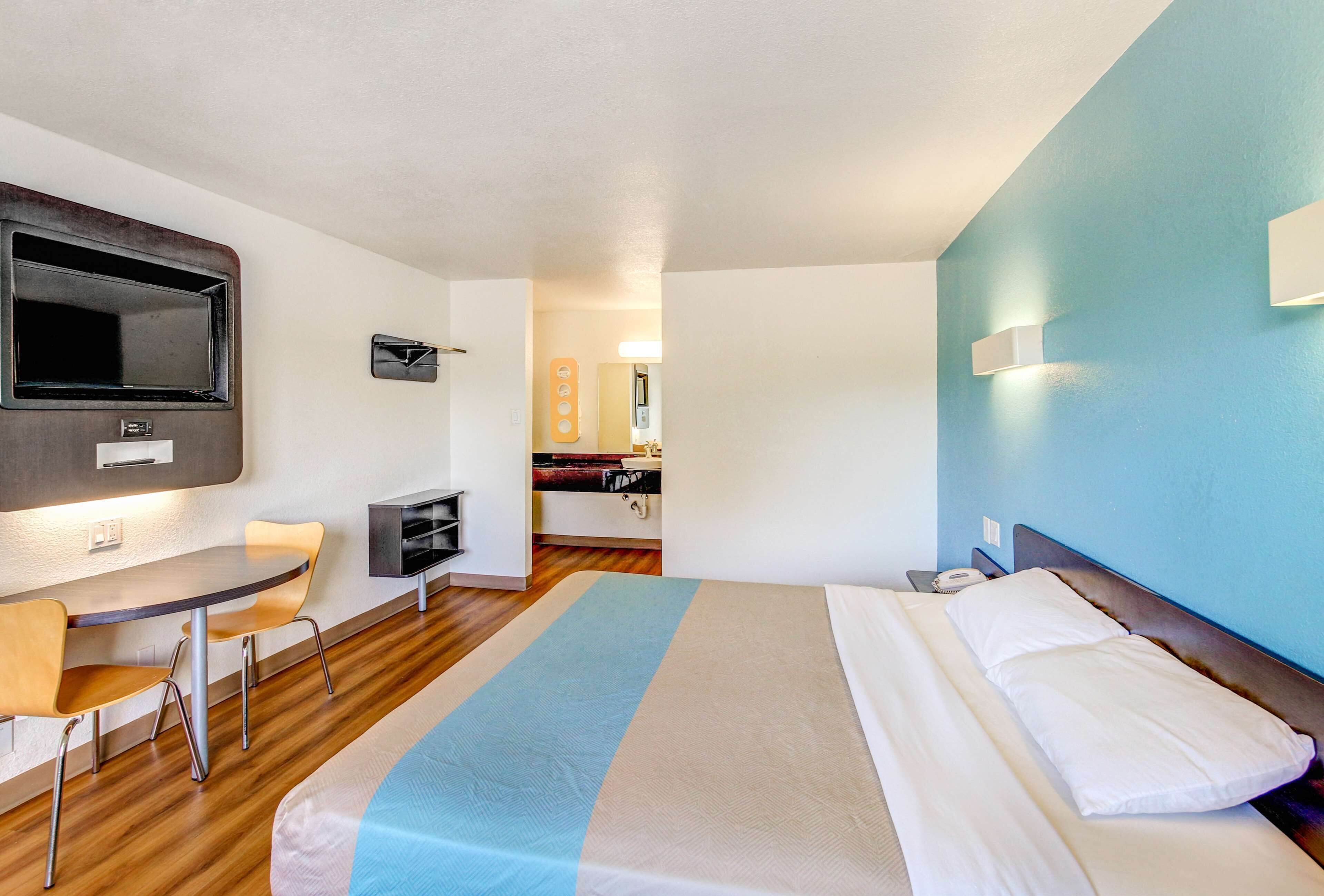 A hotel room with a bed, a desk, and a chair.