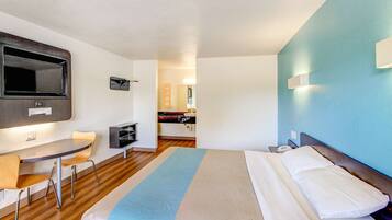 A hotel room with a bed, a desk, and a chair.