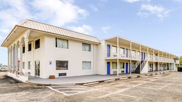 A motel with a two-story structure, a covered parking area, and a clear sky.