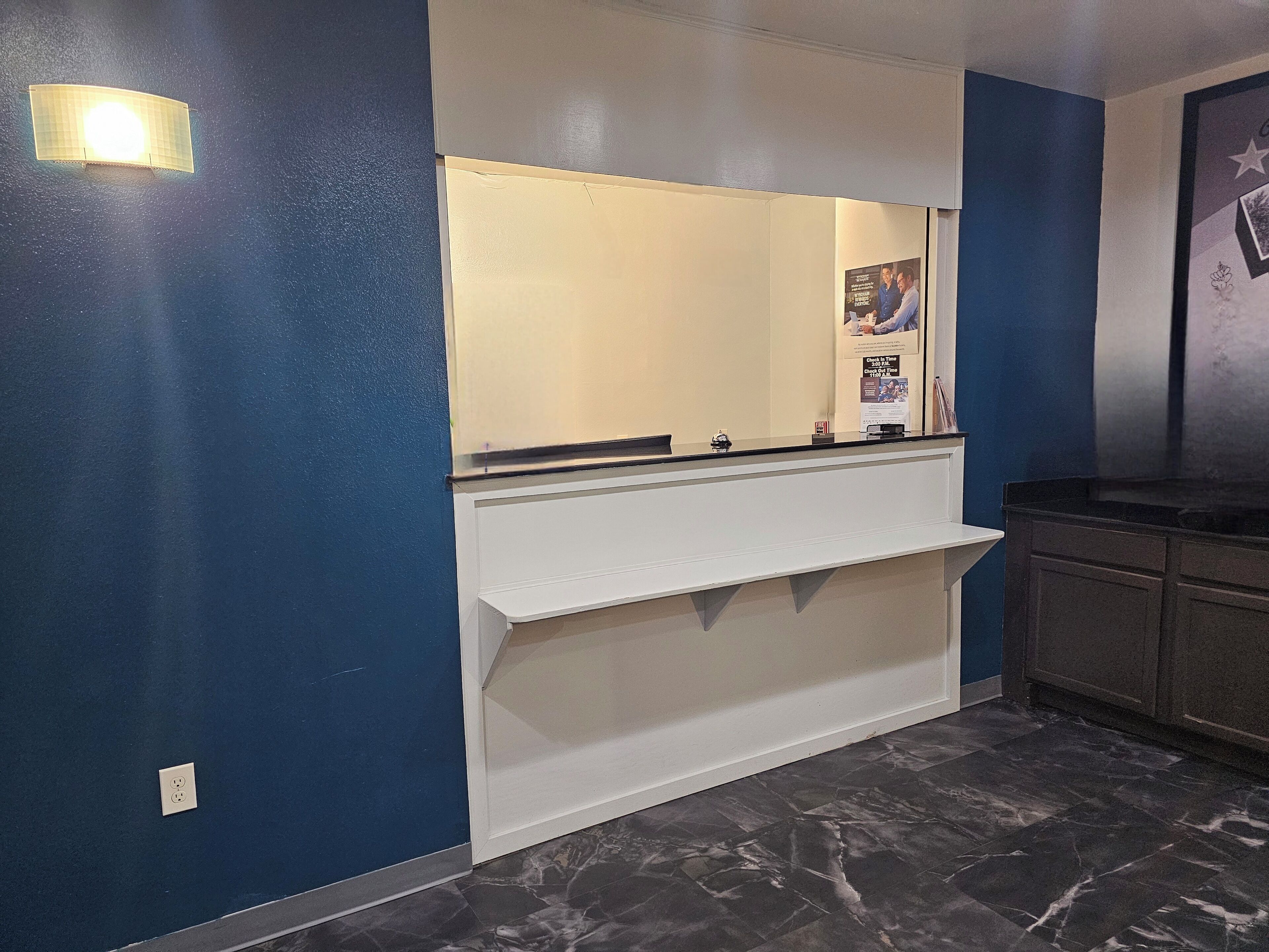 A bathroom with a white vanity, dark marble flooring, and a blue accent wall.