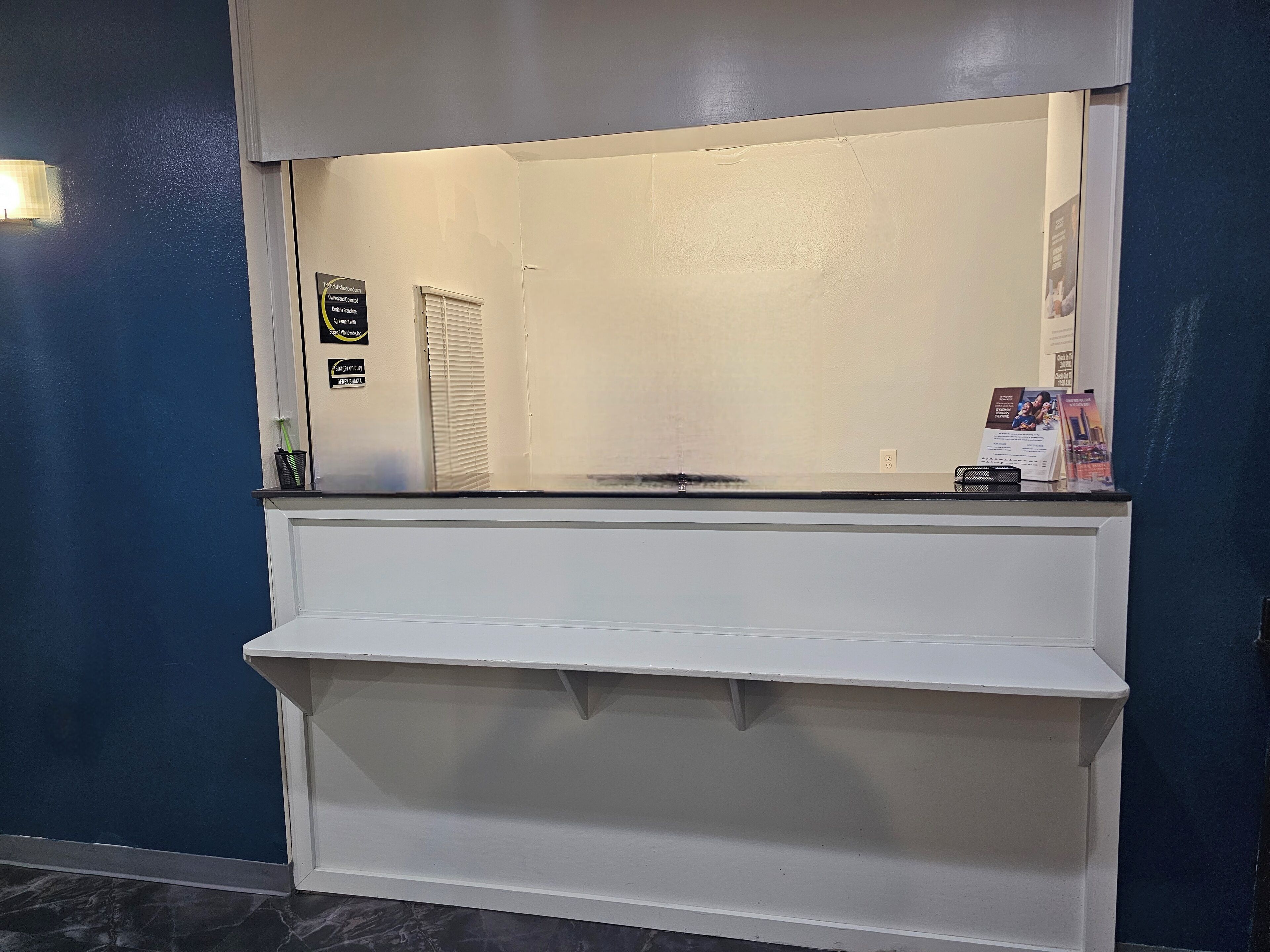 A hotel reception area with a counter, a wall-mounted sign, and a door with a window.