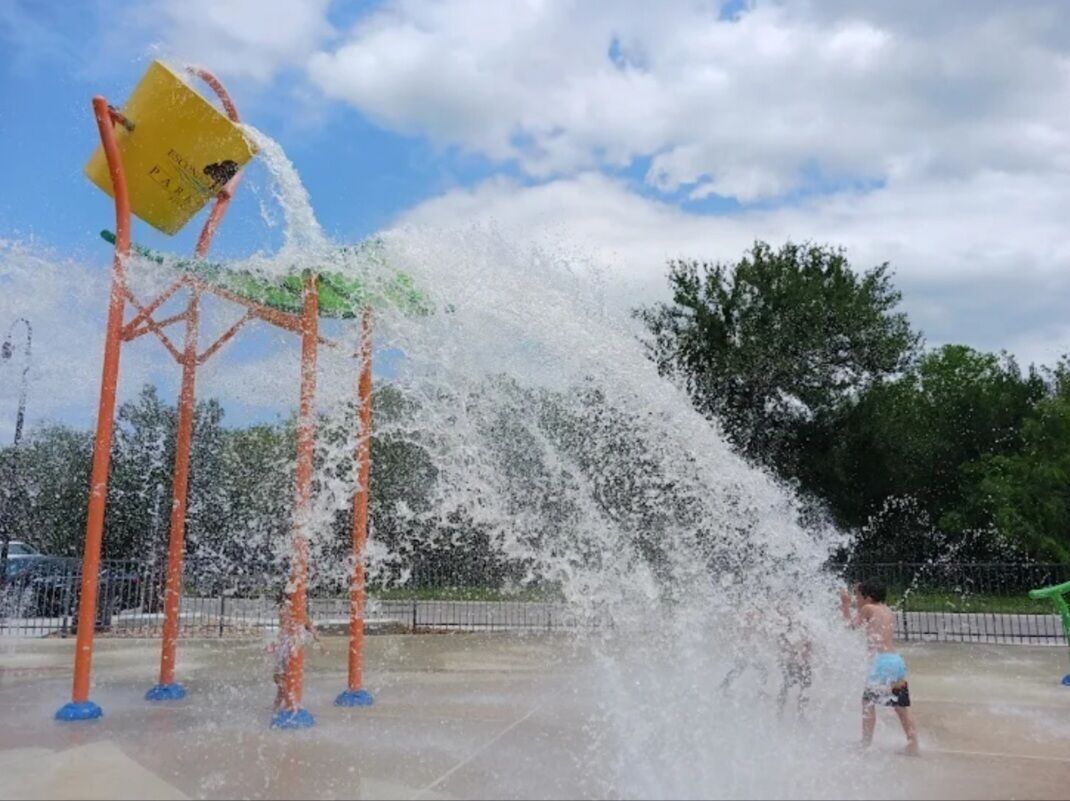 A water play area with multiple water jets and a yellow sign.